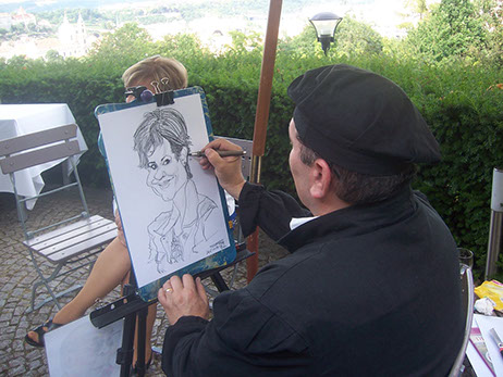 Svatební karikaturista Janko kreslí hosty na terase restaurace Nebozízek v Praze s výhledem na město.